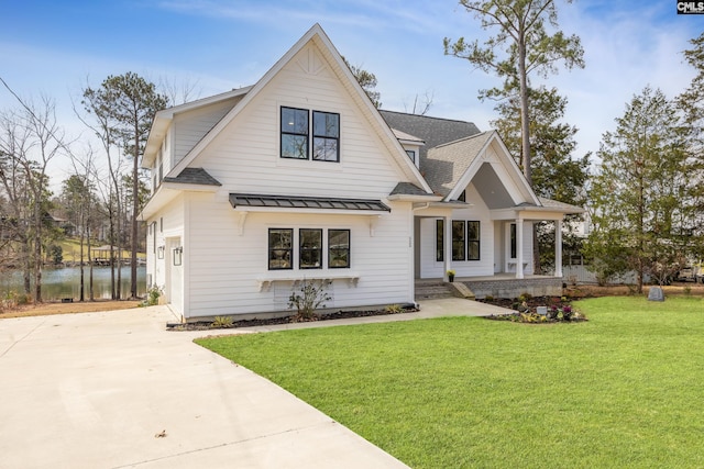 modern farmhouse featuring a standing seam roof, driveway, roof with shingles, and a front yard