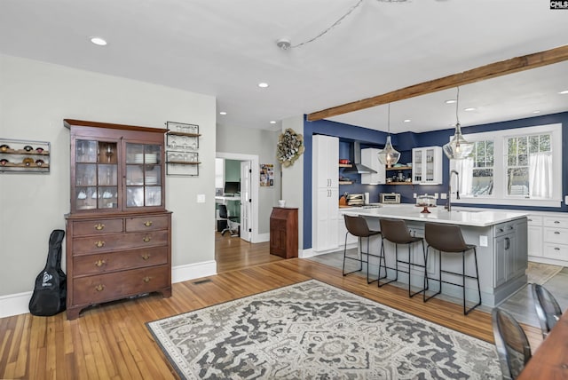 kitchen featuring white cabinets, glass insert cabinets, light countertops, pendant lighting, and a sink