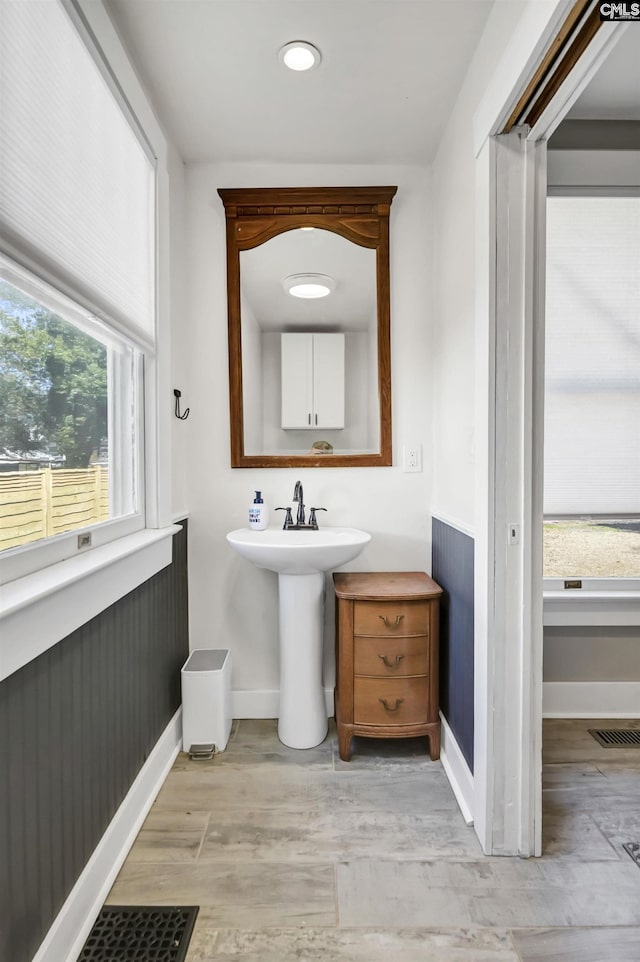 bathroom with a sink, wood finished floors, visible vents, and baseboards