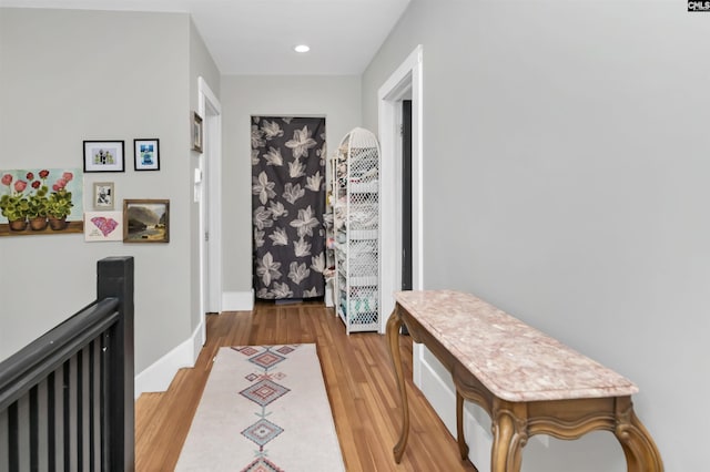 corridor with an upstairs landing, recessed lighting, baseboards, and wood finished floors