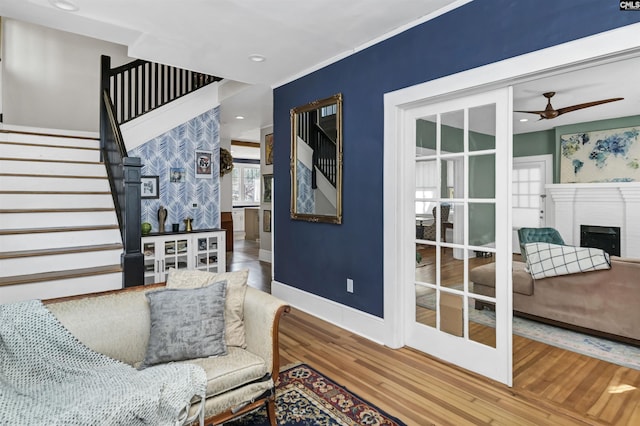 sitting room featuring baseboards, ceiling fan, wood finished floors, stairs, and a fireplace