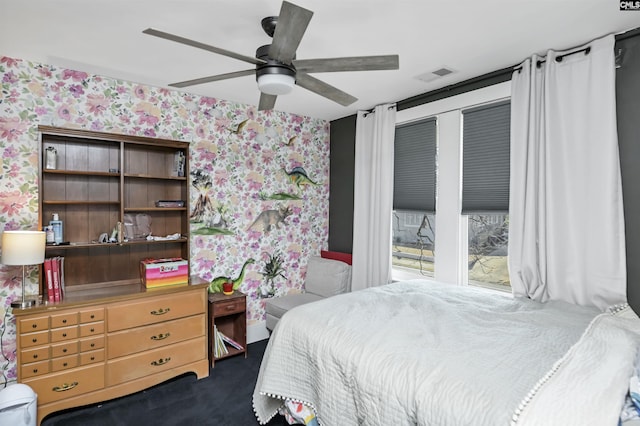 bedroom featuring a ceiling fan, visible vents, dark carpet, and wallpapered walls