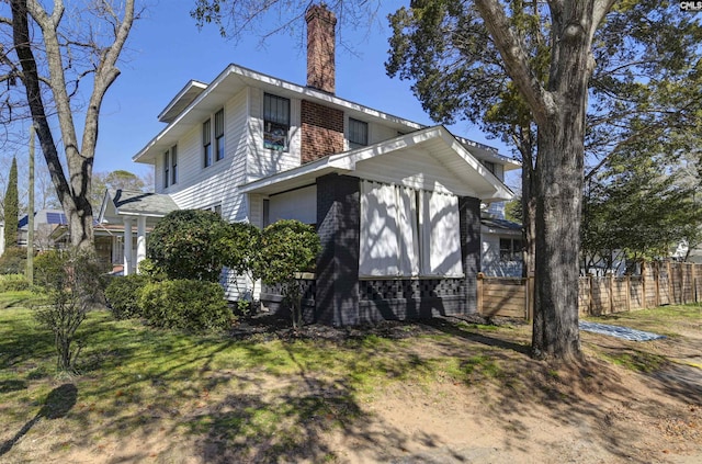 exterior space with a chimney, fence, and a lawn