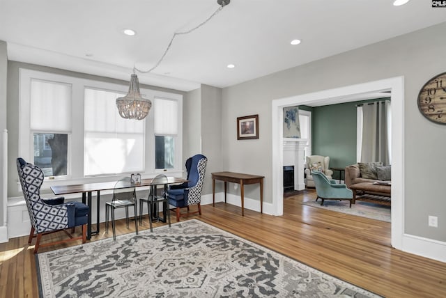 dining room with recessed lighting, a fireplace, wood finished floors, baseboards, and an inviting chandelier