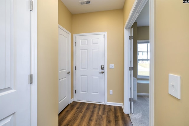 doorway with dark wood-type flooring, visible vents, and baseboards