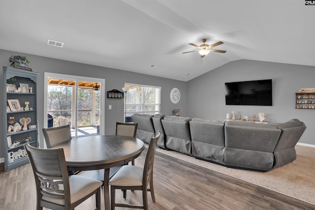 dining space featuring light wood-style floors, visible vents, vaulted ceiling, and a ceiling fan