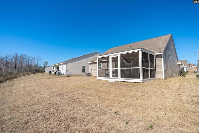 back of house featuring a sunroom, central AC unit, and a lawn