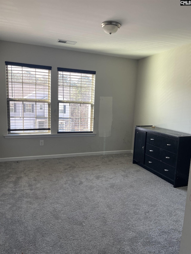 carpeted spare room featuring visible vents and baseboards