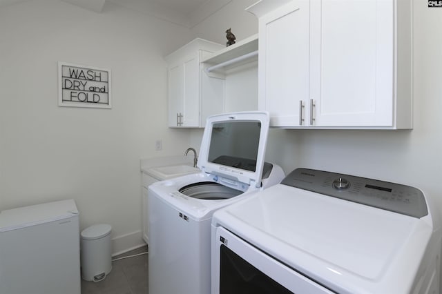 laundry room with cabinet space, tile patterned flooring, a sink, washer and dryer, and baseboards