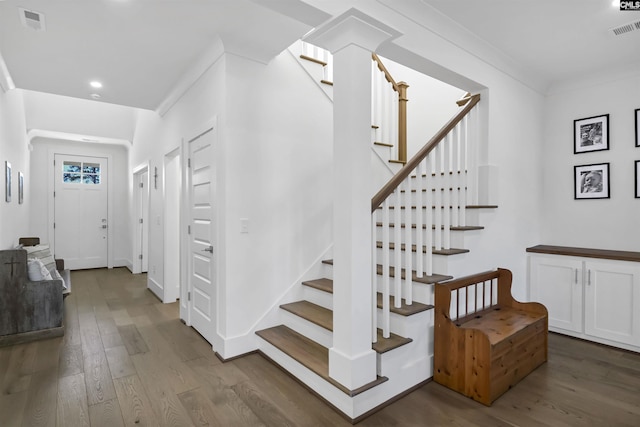 staircase featuring baseboards, visible vents, wood finished floors, and ornamental molding