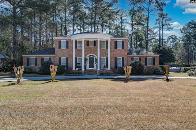 greek revival inspired property with a front lawn and brick siding