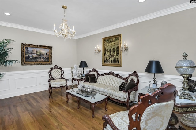 living area with a wainscoted wall, crown molding, a notable chandelier, and wood finished floors