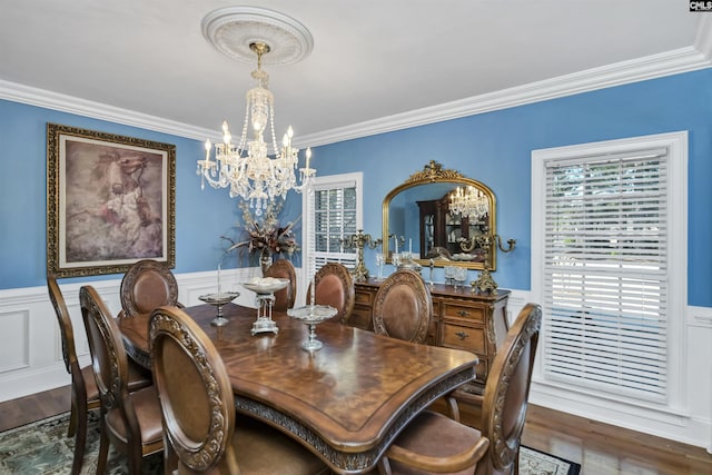 dining room featuring a wainscoted wall, a notable chandelier, ornamental molding, and wood finished floors