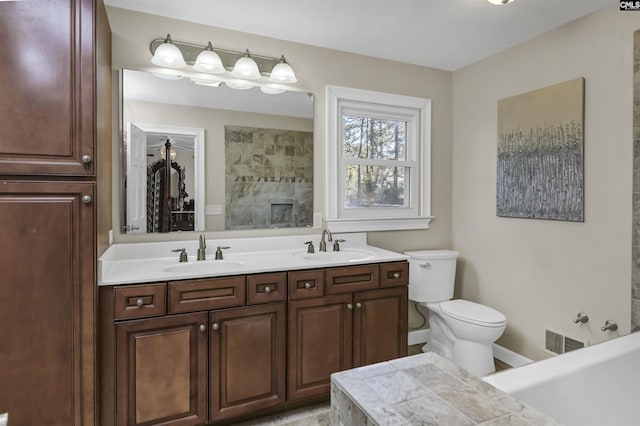 bathroom featuring toilet, visible vents, a tile shower, and a sink