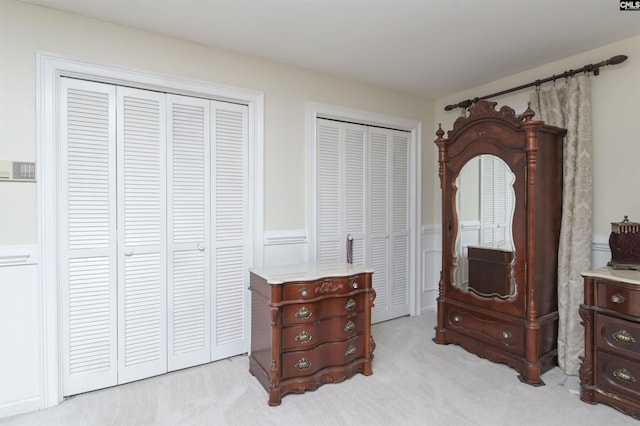 bedroom with multiple closets and light colored carpet