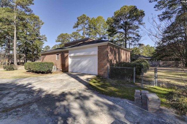 view of side of home with a gate, brick siding, fence, and driveway