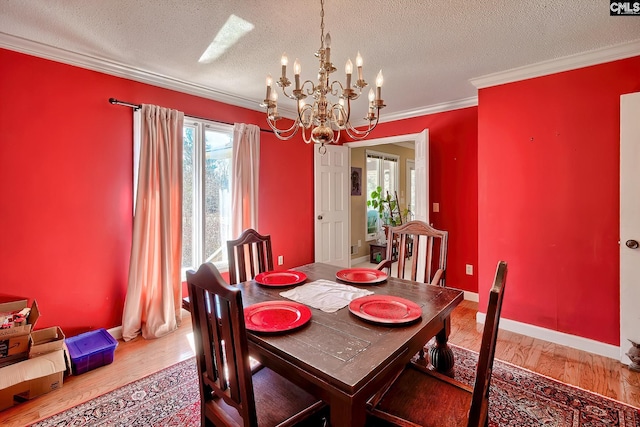 dining area with a textured ceiling, light wood-type flooring, an inviting chandelier, and crown molding