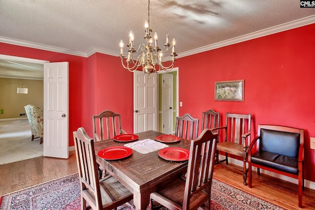 dining area featuring a notable chandelier, crown molding, a textured ceiling, and wood finished floors