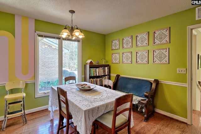 dining room with hardwood / wood-style flooring, plenty of natural light, visible vents, and a textured ceiling