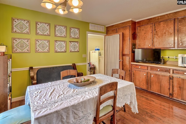 dining area featuring wood finished floors, visible vents, and an inviting chandelier