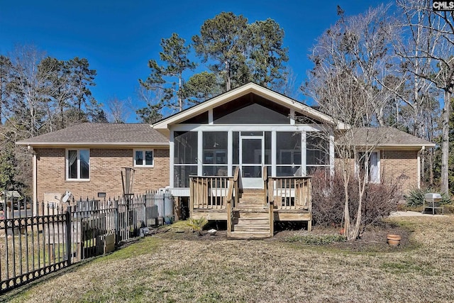 back of property featuring a sunroom, fence, a lawn, and brick siding