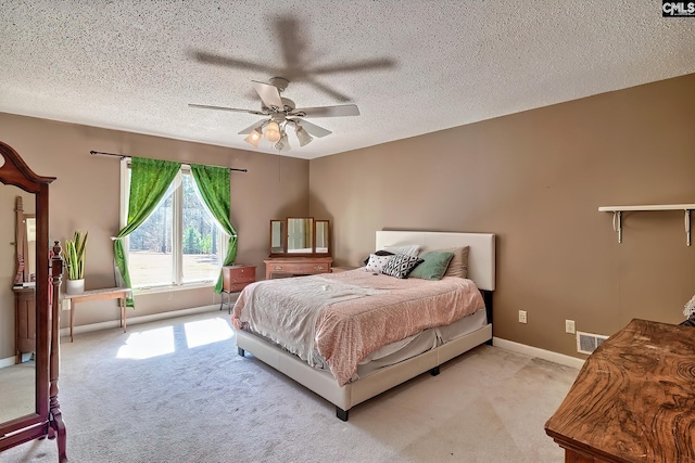 bedroom with a textured ceiling, baseboards, visible vents, and light colored carpet