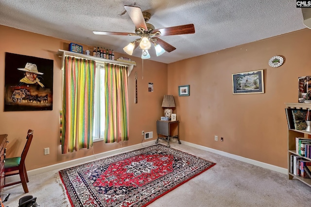 carpeted office featuring a textured ceiling, a ceiling fan, and baseboards