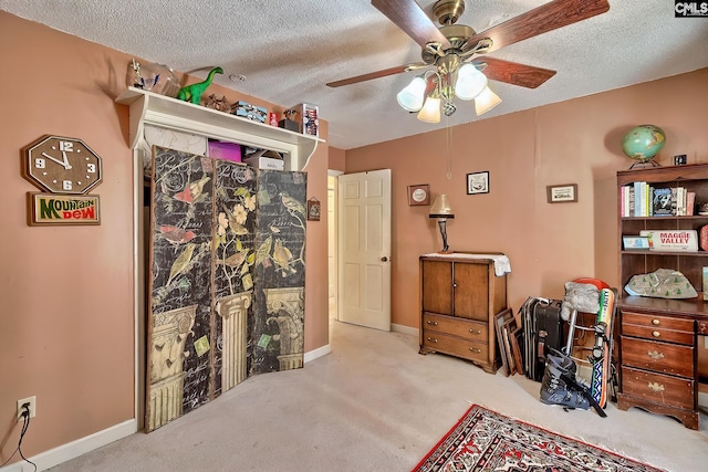 carpeted bedroom with ceiling fan, a textured ceiling, and baseboards