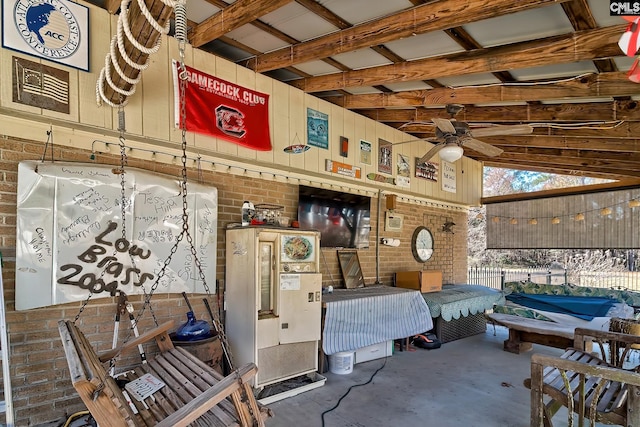 interior space featuring a ceiling fan, concrete floors, and brick wall