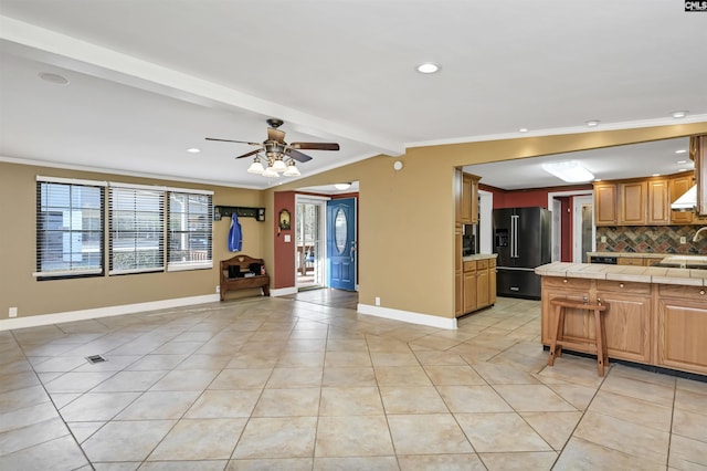 kitchen with high quality fridge, open floor plan, tile counters, tasteful backsplash, and crown molding