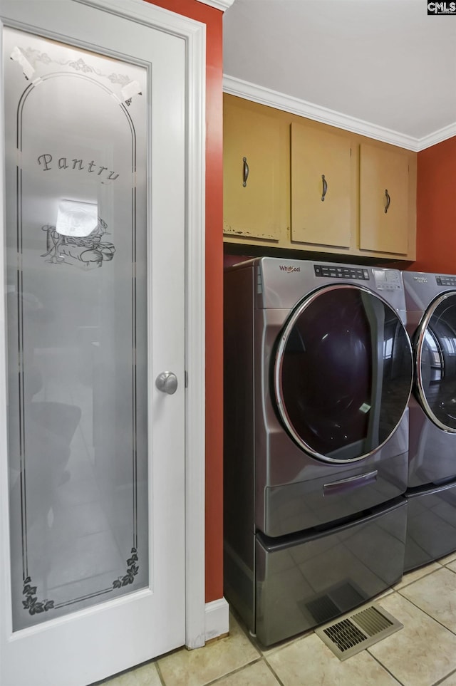 clothes washing area featuring ornamental molding, cabinet space, washer and clothes dryer, and light tile patterned floors