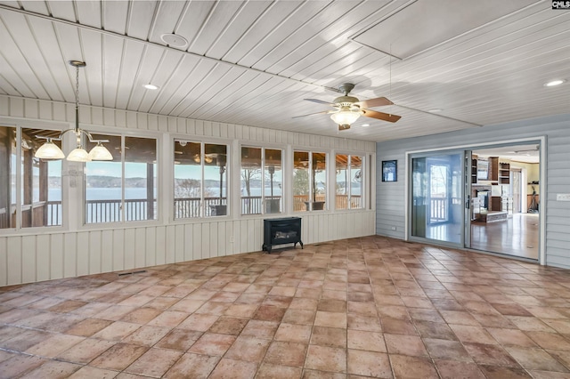 unfurnished sunroom featuring ceiling fan with notable chandelier, wooden ceiling, and a wood stove