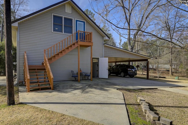 view of side of home featuring an attached carport, driveway, and stairs