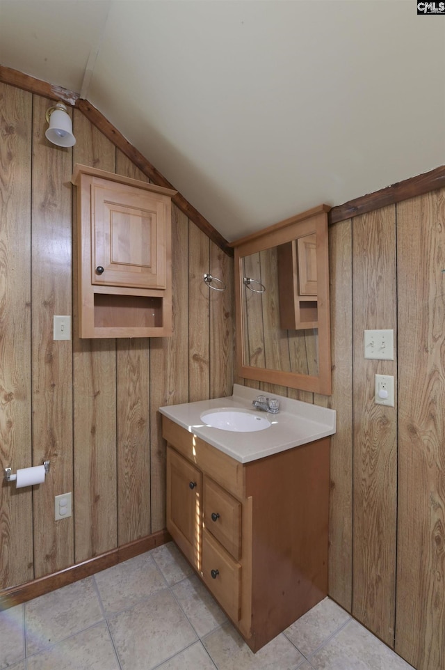 bathroom with lofted ceiling, wooden walls, and vanity