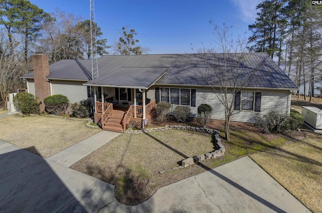 ranch-style house featuring metal roof, a porch, and a front yard