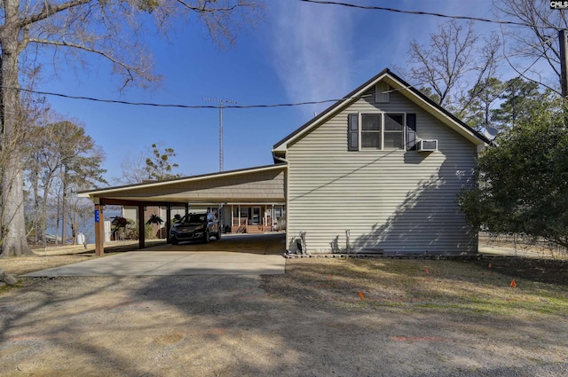 view of property exterior with an attached carport, cooling unit, and driveway