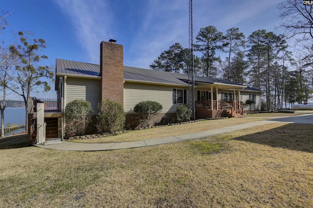 view of side of property with a chimney, stairway, metal roof, a yard, and a porch