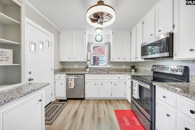 kitchen with stainless steel appliances, light wood-type flooring, a sink, and white cabinetry