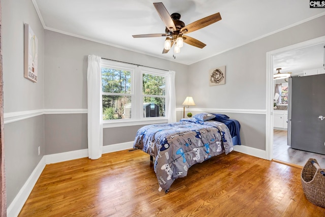 bedroom featuring ceiling fan, ornamental molding, wood finished floors, and baseboards