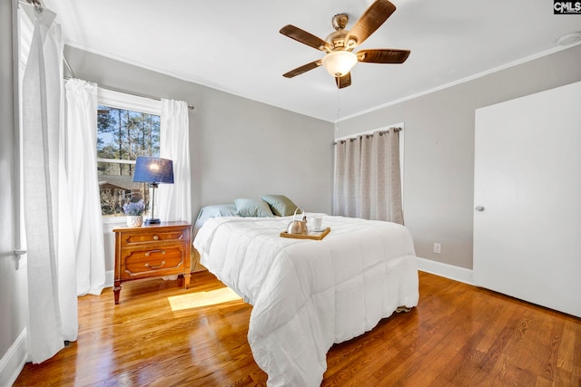 bedroom with ornamental molding, ceiling fan, baseboards, and wood finished floors