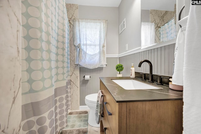 bathroom with curtained shower, visible vents, toilet, wainscoting, and vanity