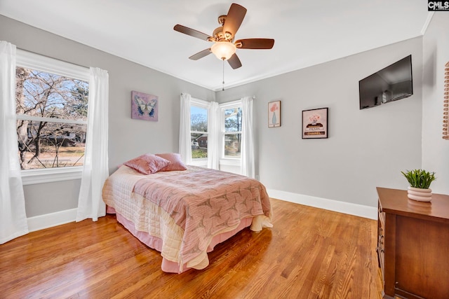 bedroom with light wood-style floors, ceiling fan, and baseboards