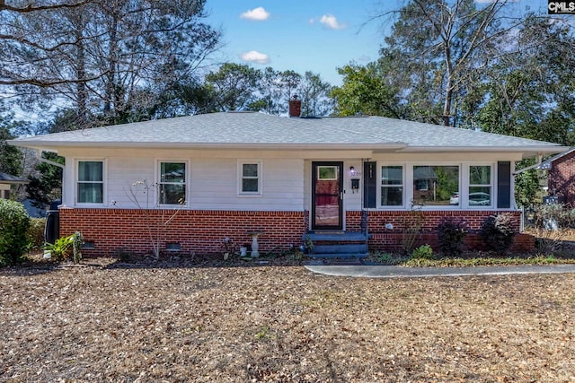 view of front of property with a shingled roof, crawl space, brick siding, and a chimney