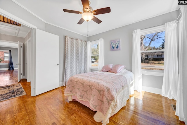 bedroom featuring visible vents, multiple windows, wood finished floors, and attic access