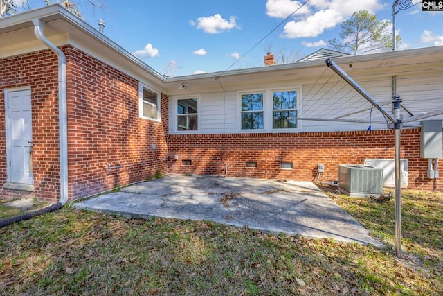 view of property exterior featuring a patio, brick siding, crawl space, and cooling unit