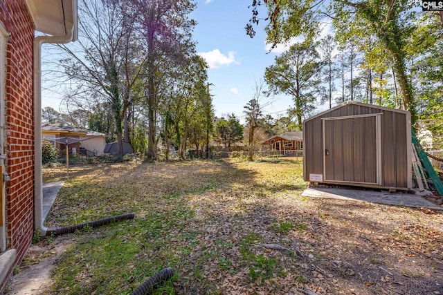 view of yard featuring an outbuilding, fence, and a storage shed