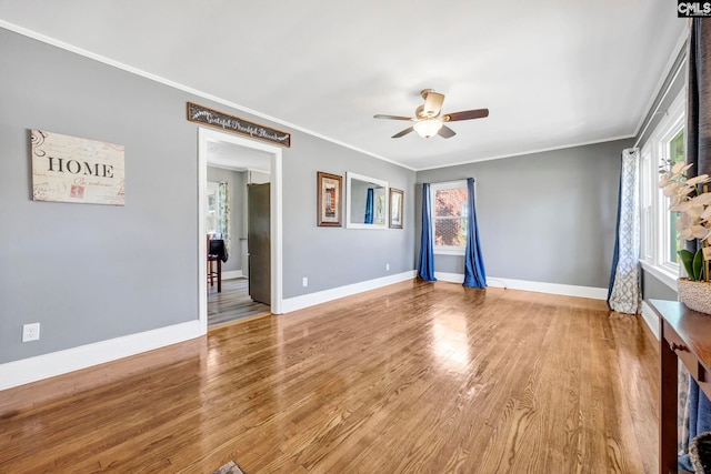 spare room featuring a ceiling fan, crown molding, baseboards, and wood finished floors