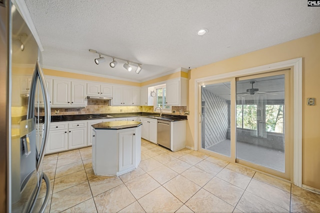 kitchen featuring under cabinet range hood, white cabinets, appliances with stainless steel finishes, backsplash, and dark countertops