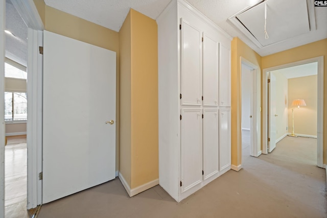 hallway with attic access and baseboards