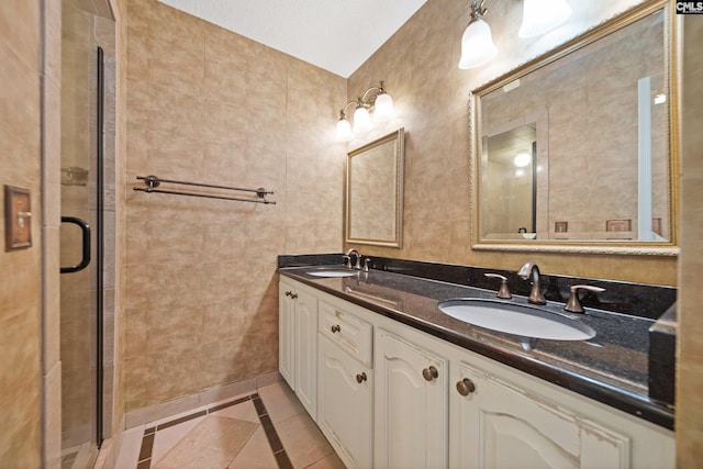 bathroom with double vanity, a stall shower, tile walls, and a sink